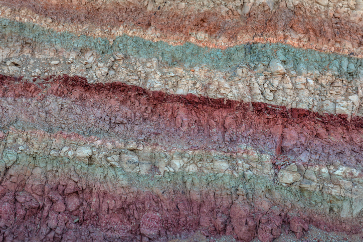 Geological layers in light shades of orange, teal, and maroon.