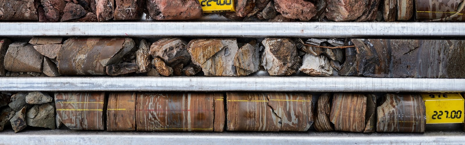 Cylindrical rock core samples laid out in metal core boxes